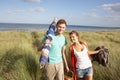 Young Couple Carrying Picnic Basket And Windbreak