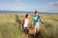 Young Couple Carrying Picnic Basket And Windbreak