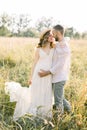 Young couple, Caucasian man and his pregnant wife in a field. Happy family resting on the wild field or meadow in summer Royalty Free Stock Photo