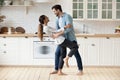Young couple celebrate housewarming dancing barefoot in modern cozy kitchen Royalty Free Stock Photo