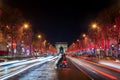 Young couple on Champs Elysees avenue and the Arc de Triomphe decorated with red Christmas lights at night in Paris France. Chri