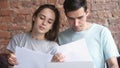 Young couple checking discussing documents, paying bills online at home