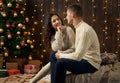 Young couple in christmas lights and decoration, dressed in white, fir tree on dark wooden background, winter holiday concept Royalty Free Stock Photo