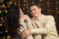 Young couple in christmas lights and decoration, dressed in white, fir tree on dark wooden background, winter holiday concept Royalty Free Stock Photo