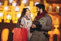 Couple in the city centre with holiday`s brights in background. Couple browsing digital tablet. They are using credit card Royalty Free Stock Photo