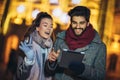 Couple in the city centre with holiday`s brights in background. Couple browsing digital tablet. They are using credit card Royalty Free Stock Photo