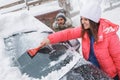 Young couple cleaning snow from car on winter day Royalty Free Stock Photo