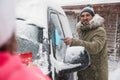 Young couple cleaning snow from car on winter day Royalty Free Stock Photo