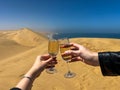 Young couple clink glasses with champagne. Sandwich Harbour in Namibia at coast.