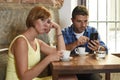 Young couple at coffee shop with internet and mobile phone addict man ignoring frustrated woman Royalty Free Stock Photo