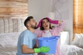 Young couple collecting leaking water from ceiling in bedroom. Time to call roof service Royalty Free Stock Photo