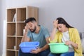 Young couple collecting leaking water from ceiling at home. Time to call roof repair service Royalty Free Stock Photo