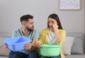 Young couple collecting leaking water from ceiling at home. Time to call roof service Royalty Free Stock Photo