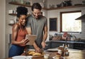 Young couple cooking healthy food together following recipes online on a tablet, step by step. Happy, cheerful and Royalty Free Stock Photo