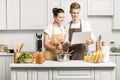 young couple cooking pasta and using laptop