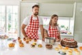 Young couple cooking pastries at the kitchen looking away to side with smile on face, natural expression Royalty Free Stock Photo