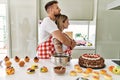 Young couple cooking pastries at the kitchen looking to side, relax profile pose with natural face with confident smile Royalty Free Stock Photo