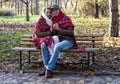 Young couple covered in plaid sitting on bench Royalty Free Stock Photo