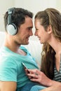 Young couple cuddling while listening to music on mobile phone Royalty Free Stock Photo