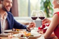 Young couple on date in restaurant sitting eating salad drinking wine cheers smiling cheerful close-up Royalty Free Stock Photo