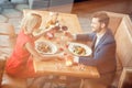 Young couple on date in restaurant sitting eating salad holding wine glasses cheers holding hands cheerful top view Royalty Free Stock Photo