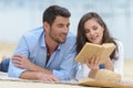Young couple dating on beach reading book Royalty Free Stock Photo