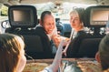 Young couple with daughters eating just cooked Italian pizza sitting in modern car with transparent roof. Happy family moments,