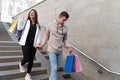 Young couple descending stairs with numerous packages after shopping