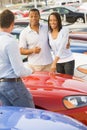Young couple discussing new car with salesman Royalty Free Stock Photo