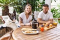 Young couple with dog smiling happy having breakfast at terrace Royalty Free Stock Photo