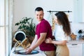 Young couple doing housework. Man cleaning dishes in kitchen and girlfriend hugging him from behind. Lifestyle Royalty Free Stock Photo