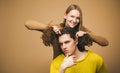 Young couple doing a joke over the isolated khaki background. A blonde girlfriend making funny hairstyle to her Royalty Free Stock Photo