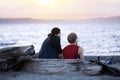 Young couple on driftwood log talking on beach at sunset Royalty Free Stock Photo