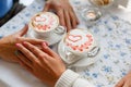 Young couple drink coffee in love clasping hands across the table in cafe, closeup. Romantic background, two cups of coffee and ha Royalty Free Stock Photo