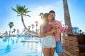 Young couple drinking cocktail in pool resort