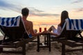 Young couple drinking cocktails on a beach at sunset during vacation