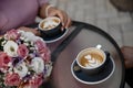 Young couple is drinking cofee. Two cups of cofee standing on the cofee table alongside with the flower pot closeup Royalty Free Stock Photo