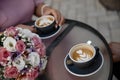 Young couple is drinking cofee. Two cups of cofee standing on the cofee table alongside with the flower pot closeup