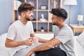 Young couple drinking coffee sitting on bed at bedrooom