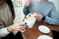 Young couple drinking hot beverages. Close up woman and man sitting in cafe, holding warm cups of coffee on table. Man and woman Royalty Free Stock Photo