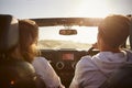 Young couple driving with sunroof open, rear passenger POV