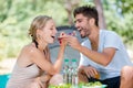 Young couple eating from eachothers forks while camping