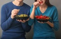Young couple eating grapes and chili on grey background Royalty Free Stock Photo