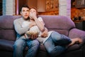 Young couple eating popcorn and watching a movie at home on the couch, scared. Royalty Free Stock Photo