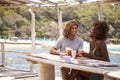 Young couple eating at a table by the sea look at each other Royalty Free Stock Photo