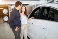 Young couple in elegant summer time clothes choose a new car at car dealership Royalty Free Stock Photo