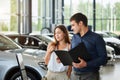 Young couple in elegant summer time clothes choose a new car at car dealership Royalty Free Stock Photo