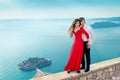 Young couple embraccing over the sea on romantic travel honeymoon vacation summer holidays romance. Gorgeous girl in red dress wi Royalty Free Stock Photo