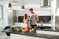 Young Couple Embrace In Kitchen, Hispanic Man And Asian Woman Hug Drink Wine Royalty Free Stock Photo