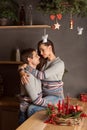 Young couple embracing gently and passionately kissing in the kitchen under the mistletoe on Christmas new year